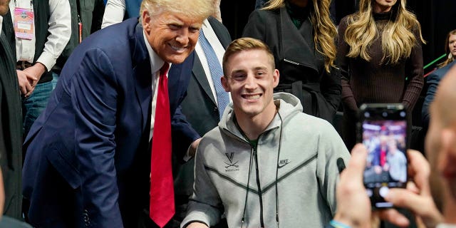 El expresidente Donald Trump, a la izquierda, posa para una foto con el luchador de Virginia, Justin McCoy, en el Campeonato de Lucha Libre de la NCAA, el sábado 18 de marzo de 2023, en Tulsa, Oklahoma.