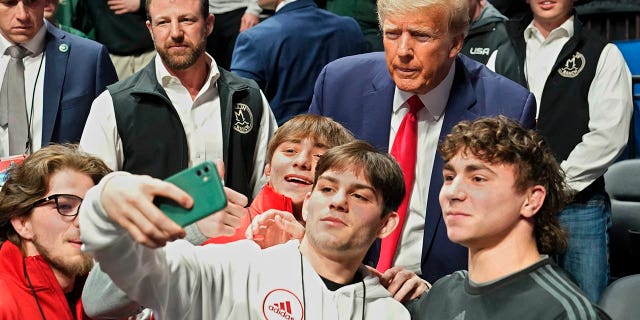 Former President Donald Trump, right, poses for photos at the NCAA Championship Wrestling Championship, Saturday, March 18, 2023, in Tulsa, Oklahoma.