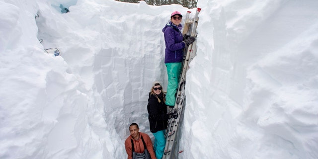 Working inside a nearly 18-foot-deep snow pit at the UC Berkeley Central Sierra Snow Lab, from left, Shaun Joseph, Claudia Norman, Helena Middleton take measurements of snow temperatures ahead of a weather storm on March 9, 2023, in Soda Springs, California.