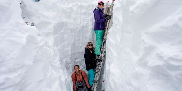 Working inside a nearly 18-foot-deep snow pit at the UC Berkeley Central Sierra Snow Lab, from left, Shaun Joseph, Claudia Norman, Helena Middleton take measurements of snow temperatures ahead of a weather storm on March 9, 2023, in Soda Springs, California.