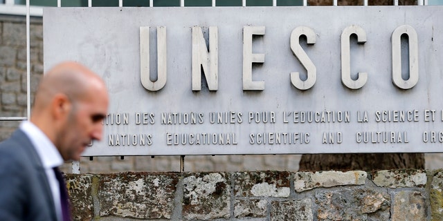 A man walks past the logo of the United Nations Educational, Scientific and Cultural Organization (UNESCO) in Paris, France. 