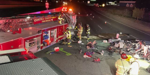 In this photo released by Contra Costa County Fire Protection District, firefighters work the scene of a fatal accident involving a Tesla and Contra Costa County fire truck early Saturday morning, Feb. 18, 2023, in Contra Costa, Calif. Fire officials said the Tesla driver was killed, and a passenger was critically injured Saturday when the car plowed into the fire truck parked on a Northern California freeway to shield a crew clearing another accident.