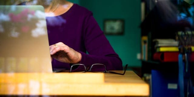 A woman sits at a desk at home working on a laptop. Finding side jobs can help you earn that extra cash to bolster your savings and investments.