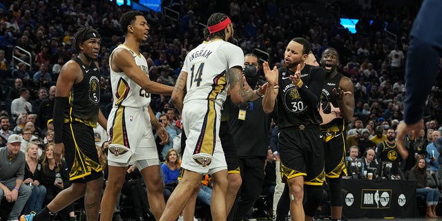 Stephen Curry #30 and Draymond Green #23 of the Golden State Warriors talk to Brandon Ingram #14 of the New Orleans Pelicans following a scuffle during the second quarter at Chase Center on March 28, 2023 in San Francisco, California.