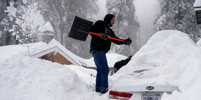 Kenny Rybak, 31, shovels snow around his car in Running Springs, California, Tuesday, Feb. 28, 2023.