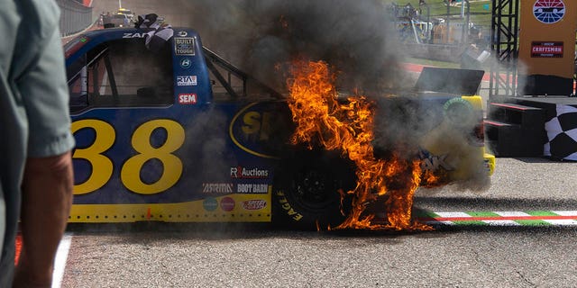El fuego se propaga a la camioneta de Zane Smith luego de su agotamiento después de ganar una carrera de autos de la Serie de Camionetas de NASCAR, el sábado 25 de marzo de 2023, en Austin.