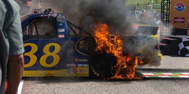 Fire spreads over Zane Smith's truck following his celebratory burnout after winning a NASCAR Truck Series auto race, Saturday, March 25, 2023, in Austin.