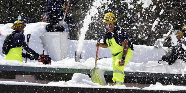 Members of a Cal Fire crew clear snow off the roof of the town's post office after a series of storms Wednesday, March 8, 2023, in Crestline, Calif. 