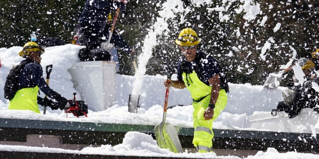 Members of a Cal Fire crew clear snow off the roof of the town's post office after a series of storms Wednesday, March 8, 2023, in Crestline, Calif. 