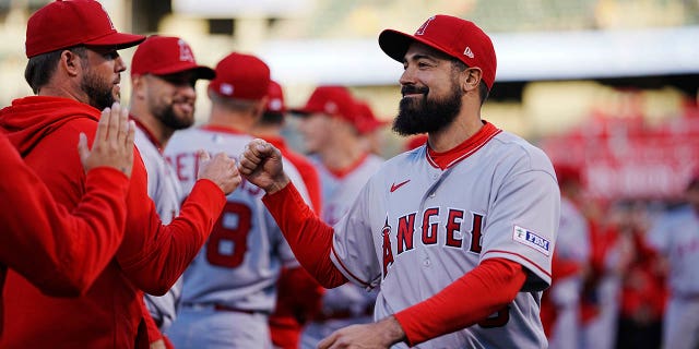 Los Angeles Angels' Anthony Rendon, right, fist bumps against coaches and teammates during a game against the Oakland Athletics at RingCentral Coliseum on Thursday, March 30, 2023, in Oakland, California. 