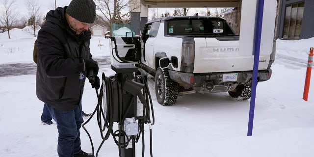 Lawrence Ziehr, project manager for energy recovery on GM's electric vehicles, connects a Hummer EV to a charging station, Wednesday, Feb. 22, 2023, in Sault Ste. Marie, Mich. Some automakers and drivers fear lower battery range in the cold could limit acceptance of electric cars, trucks and buses, at a time when emissions from transportation must go down sharply to address climate change. (AP Photo/Carlos Osorio)