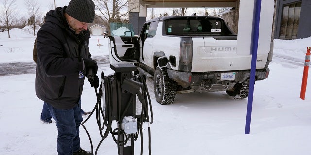 Lawrence Ziehr, project manager for energy recovery on GM's electric vehicles, connects a Hummer EV to a charging station, Wednesday, Feb. 22, 2023, in Sault Ste. Marie, Mich. Some automakers and drivers fear lower battery range in the cold could limit acceptance of electric cars, trucks and buses, at a time when emissions from transportation must go down sharply to address climate change.  (AP Photo/Carlos Osorio)