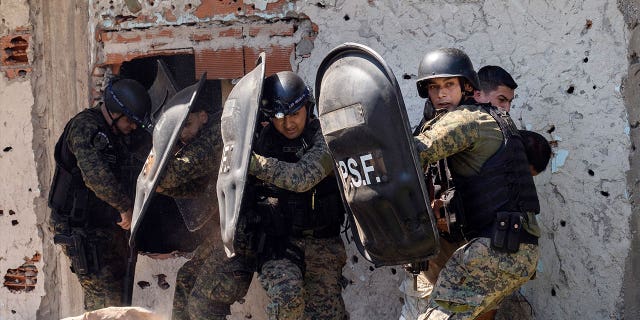 Police in riot gear protect a suspected gunman from his neighbors after an 11-year-old boy was killed in Rosario, Argentina, on March 6, 2023. 