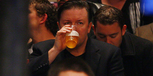 Ricky Gervais takes a sip of beer as he watches a boxing match at MSG.