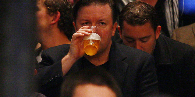 Ricky Gervais takes a sip of beer as he watches a boxing match at MSG.