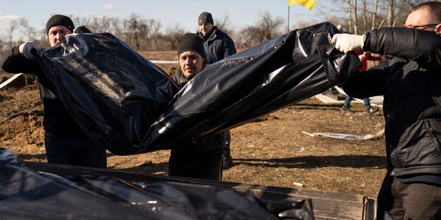 Men carry bags containing three freshly exhumed bodies at a Ukrainian cemetery March 2, 2023. Ukrainian authorities are still exhuming the bodies of civilians hastily buried in makeshift graves. 