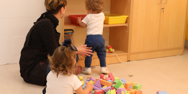Children play in a classroom with teacher.