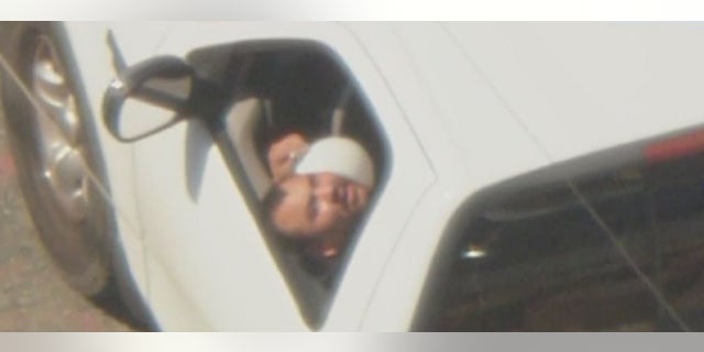 A DUI suspect sticks his head out the window of a pickup truck during a police chase in Compton, California.
