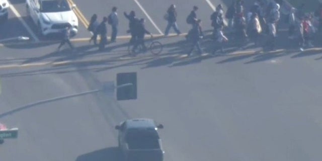 A group of children cross the street near Los Angeles on Friday as a gunman led authorities on a lengthy police chase Friday.  