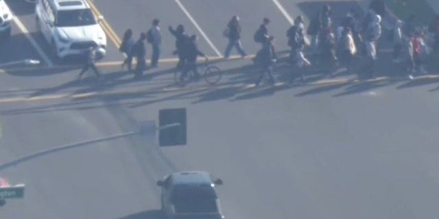 A group of children cross the street near Los Angeles on Friday as a gunman led authorities on a lengthy police chase Friday.  