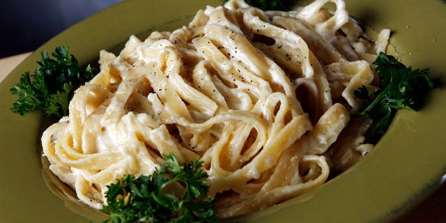 Fetucine alfredo pasta on a green dish with garnish