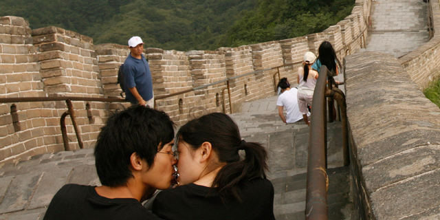 A Chinese couple kiss as they visit the Great Wall of China.
