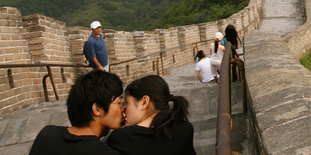 A Chinese couple kiss as they visit the Great Wall of China.