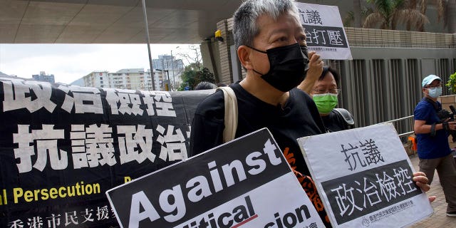 Pro-democracy activist Lee Cheuk-yan, center, holds placards as he arrives at a court in Hong Kong on April 1, 2021. Hong Kong national security police arrested March 9, 2023, Lee Cheuk-yan's wife Elizabeth Tang, a veteran labor activist.