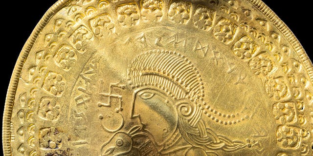 The inscription "He is Odin’s man" is seen over the head of a figure on a golden bracteate unearthed in Vindelev, Denmark, in late 2020.