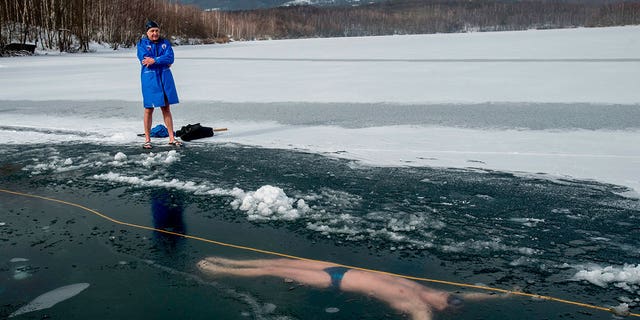 Un hombre junto al lago Barbora, cerca de la ciudad de Teplice, mientras su amigo, el buceador checo David Finkel, nada bajo el hielo en la República Checa el 13 de febrero de 2021.