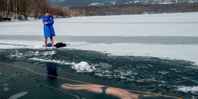 Freediver rompe récord de profundidad a 170 pies bajo un lago suizo congelado 4 Un hombre junto al lago Barbora, cerca de la ciudad de Teplice, mientras su amigo, el buceador checo David Finkel, nada bajo el hielo en la República Checa el 13 de febrero de 2021.