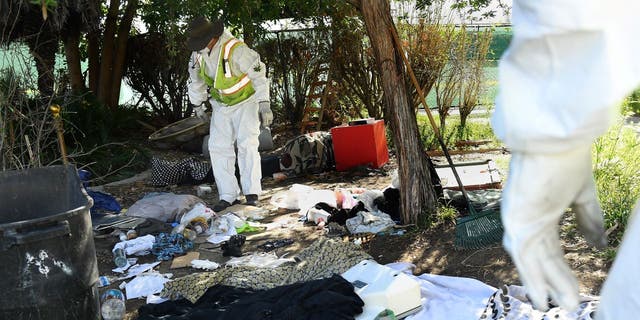 Work crews look over belongings left behind by a homeless person during clean-up in Echo Park.