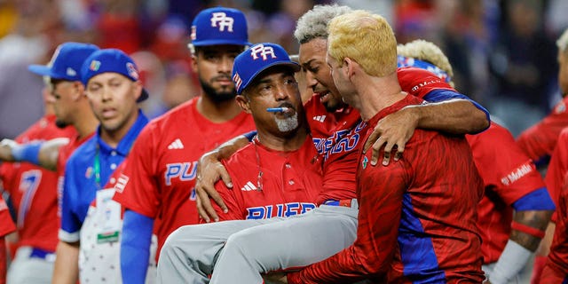 Puerto Rico pitcher Edwin Diaz (39) gets taken off the field by pitching coach Ricky Bones (27) after an apparent leg injury during the team celebration against the Dominican Republic at LoanDepot Park.