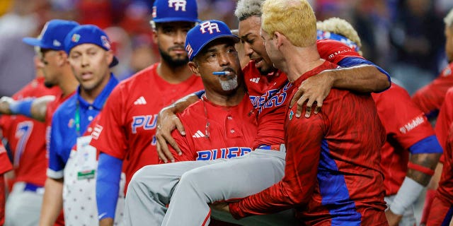 Puerto Rican pitcher Edwin Diaz (39) is taken off the field by pitching coach Ricky Bones (27) after an apparent leg injury during a team celebration against the Dominican Republic at LoanDepot Park.