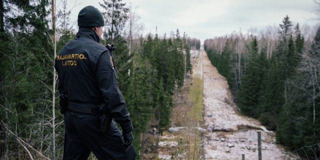 A Finnish border guard looks at a fence marking the boundary area between Finland and the Russian Federation near the border crossing of Pelkola, in Imatra, Finland on November 18, 2022. 