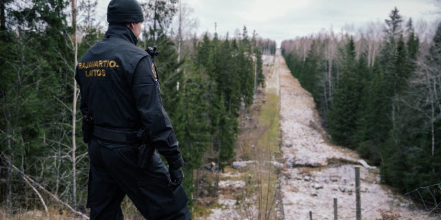 A Finnish border guard looks at a fence marking the boundary area between Finland and the Russian Federation near the border crossing of Pelkola, in Imatra, Finland on November 18, 2022. 