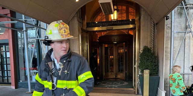 A firefighter walks out of the Sherry-Netherland Hotel in Manhattan after a two-alarm fire breaks out on the 18th floor.