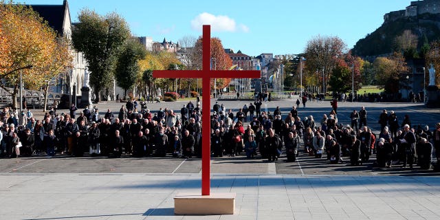 Bishops kneel on the forecourt of the Notre-Dame-du-Rosaire basilica in the sanctuary of Lourdes, southwestern France, on Nov. 6, 2021 during a ceremony, part of The Bishops' Conference.