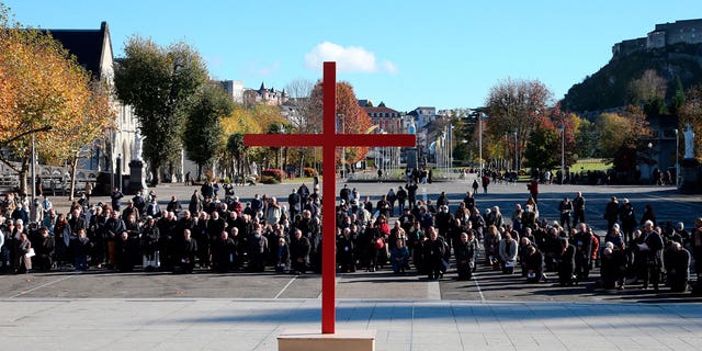 Bishops kneel on the forecourt of the basilica of Notre-Dame-du-Rosaire in the sanctuary of Lourdes, in southwestern France, November 6, 2021 during a ceremony, as part of the Episcopal Conference.