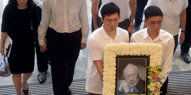 Los familiares del difunto primer ministro Lee Kuan Yew llegan con su retrato al funeral de estado en Singapur el 29 de marzo de 2015. El hermano del actual primer ministro de Singapur e hijo del difunto Lee Kuan Yew acusa a las autoridades gubernamentales de perseguir a su familia.