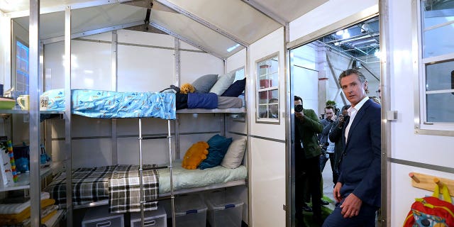 California Gov. Gavin Newsom enters the prototype of one of the small homes displayed at a news conference in Sacramento on March 16, 2023.