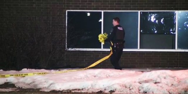 A police officer appears to be wrapping up crime scene tape following a shooting investigation that left six injured over the weekend in Brooklyn Center, Minnesota.