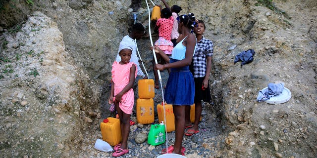 People, without running water at home, collect water from a ravine in Port-au-Prince, Haiti, on March 21, 2023.