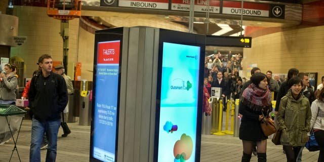 Commuters walking past the MBTA's brand-new digital advertising and information screens at the Harvard Square T Station on Thursday, January 31, 2013. 