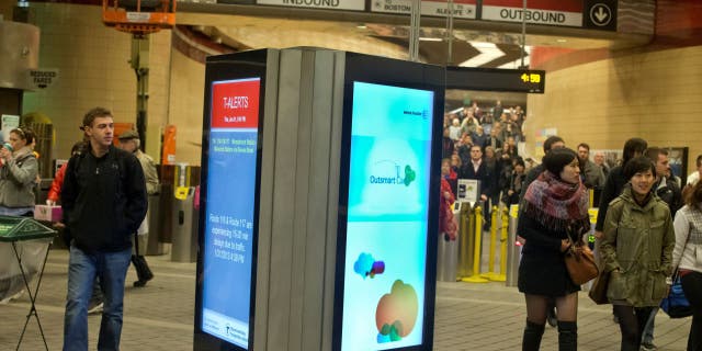 Commuters walking past the MBTA's brand-new digital advertising and information screens at the Harvard Square T Station on Thursday, January 31, 2013.