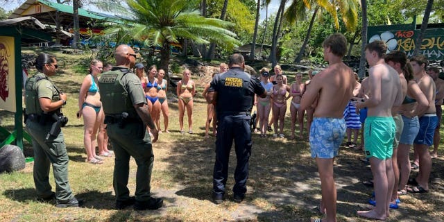Department enforcement officers speak to swimmers in Honaunau, Hawaii, on March 26, 2023, after the swimmers allegedly harassed a pod of wild spinner dolphins.