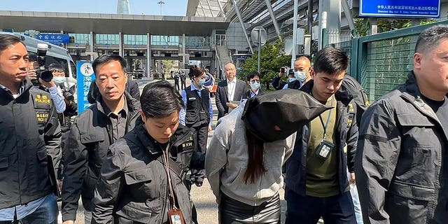 Hong Kong police escort a suspect at the Shenzhen Bay Port border crossing in Hong Kong, on March 7, 2023. The woman is accused of assisting another suspect in the gruesome killing of model Abby Choi.