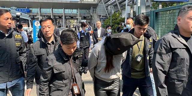 Arrestado en relación con el espantoso asesinato, desmembramiento del modelo de Hong Kong 4 La policía de Hong Kong escolta a un sospechoso en el cruce del puerto fronterizo de la bahía de Shenzhen en Hong Kong, el 7 de marzo de 2023. La mujer está acusada de ayudar a otro sospechoso en el espantoso asesinato de la modelo Abby Choi.