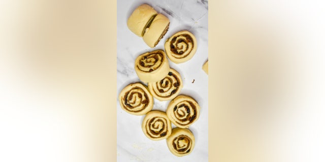 Highlight the traditional hot cross bun flavor by infusing the dried fruit with orange juice and mixing it into the cinnamon roll filling.