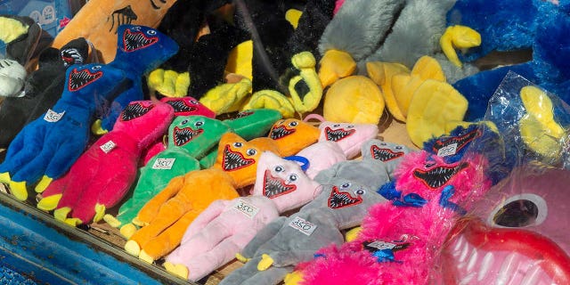 Samples of Huggy Wuggy-inspired stuffed animals are shown on a table.